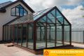 Зимний сад частного дома с панорамным остеклением профилем коричневого цвета