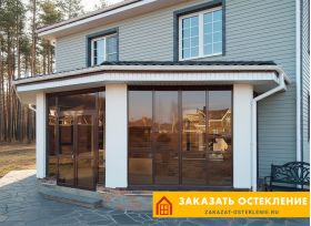 Веранда дома с остеклением профилем коричневого цвета с тонировкой